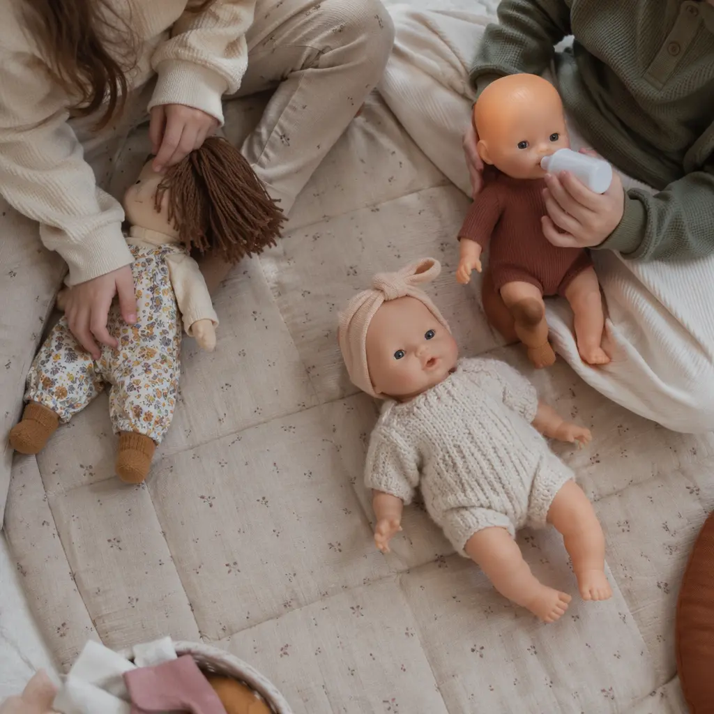 Top-down view of dolls on a play mat with no faces visible