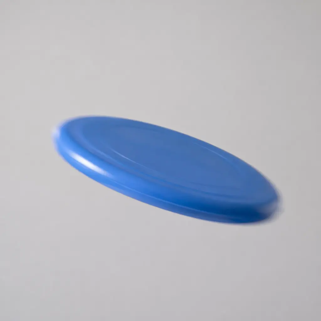 A simple plastic flying disc captured mid-flight against a clean background
