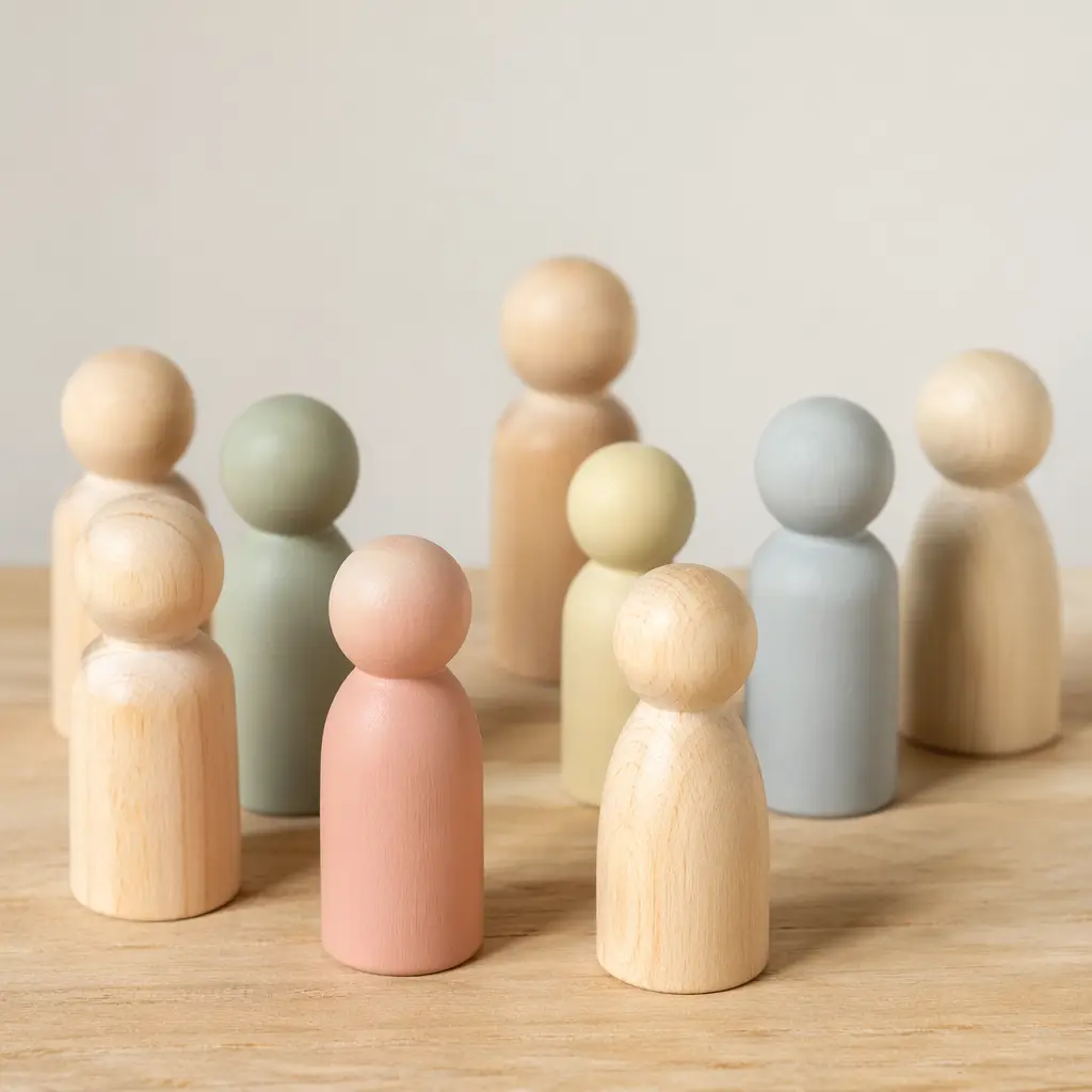 A group of simple wooden peg dolls in natural and muted colours on a wooden surface