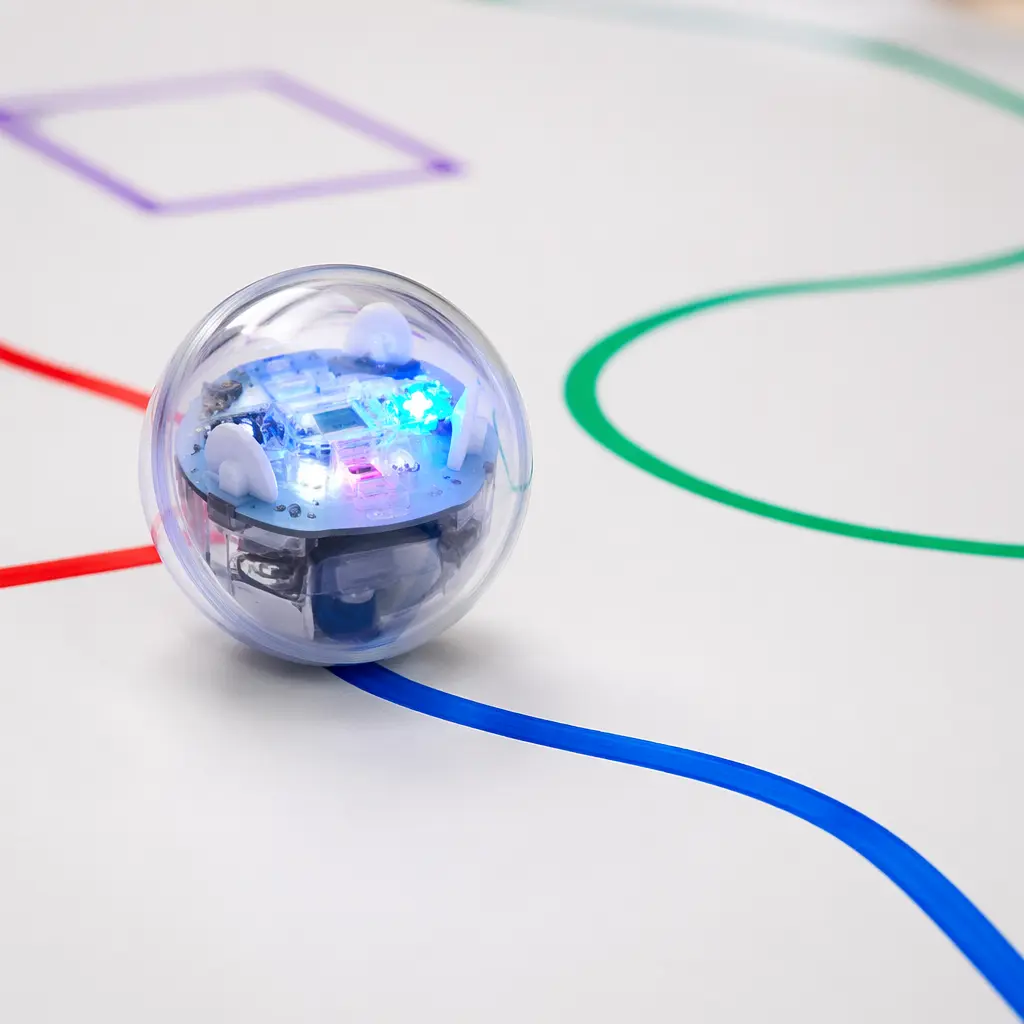 A small rolling educational robot following colorful lines drawn on paper