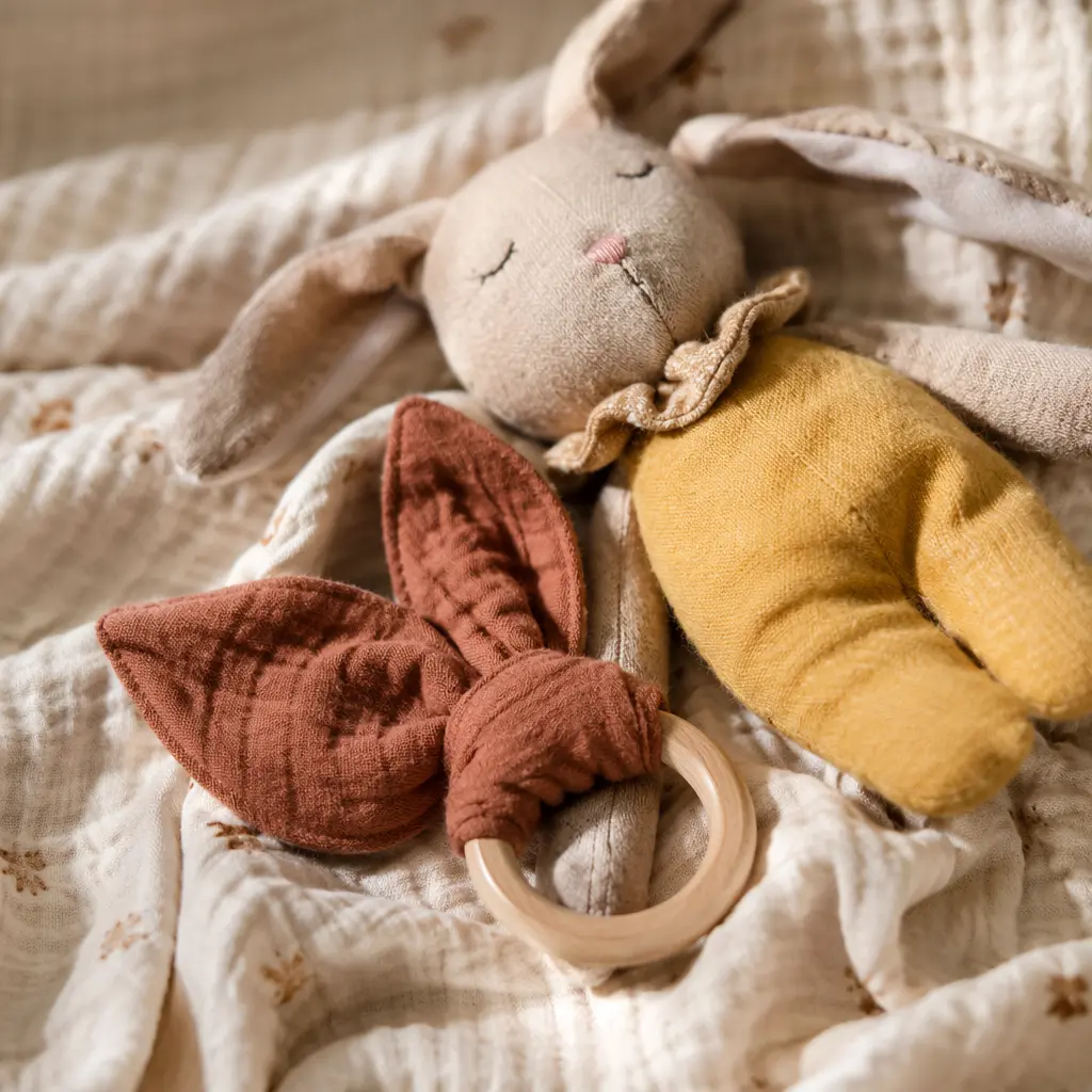 Close-up of soft fabric baby toy and wooden teether on a blanket