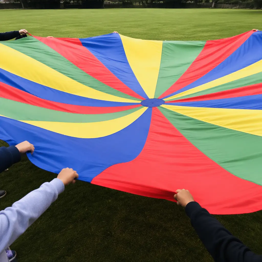 Colorful playground parachute rippling across a grassy field during group play